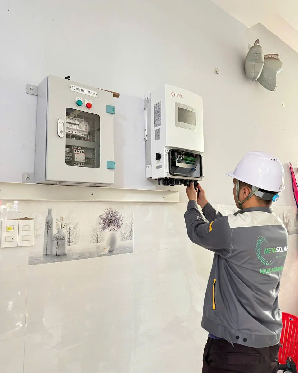 Kỹ thuật viên METASOLAR cắm đầu nối cáp vào khoang đấu dây đã mở nắp của inverter Solis gắn tường