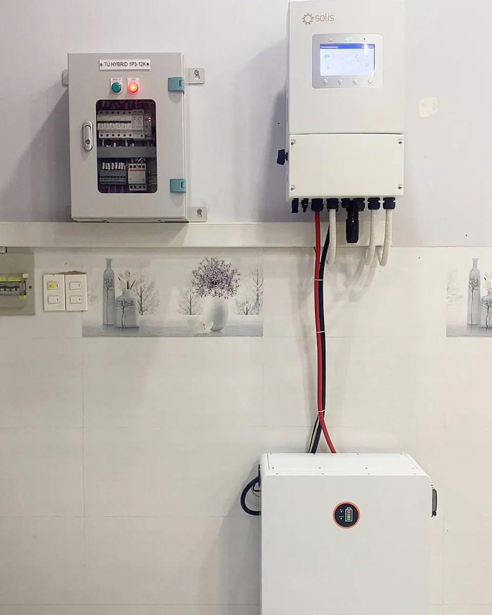 Tủ hybrid có đèn báo, inverter Solis màn hình cảm ứng và tủ pin lưu trữ gắn gọn trên tường trắng