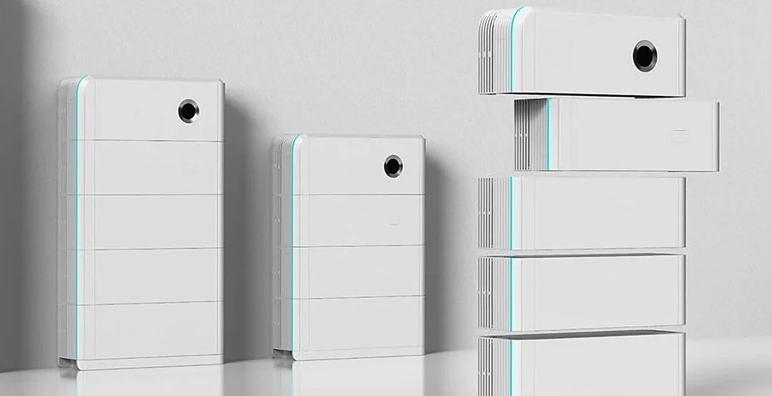 Các module pin lưu trữ vỏ trắng xếp chồng thành cột, đặt sát tường, có bộ điều khiển tròn đen ở trên cùng